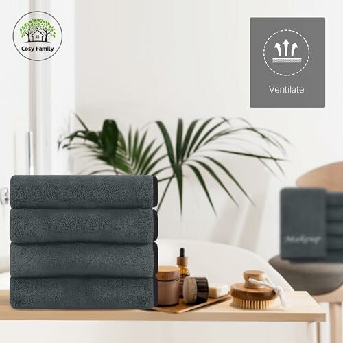 Stack of dark towels with bath accessories in modern bathroom.