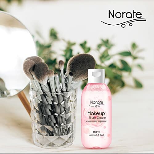 Makeup brush cleaner bottle next to a glass with makeup brushes.