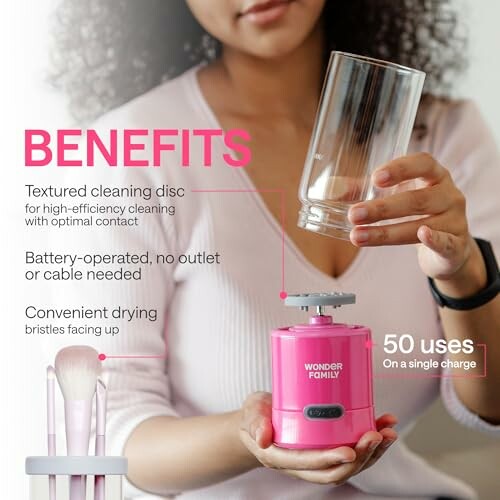 Person using a pink battery-operated makeup brush cleaning device.